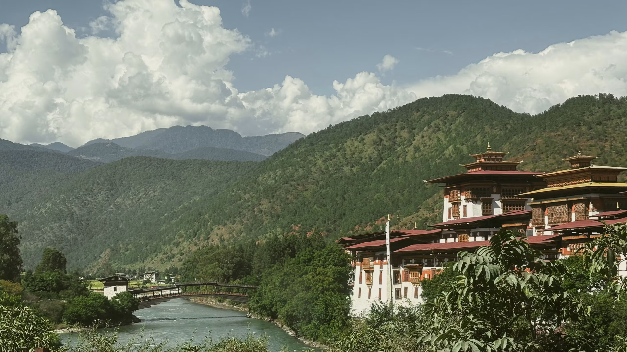 Arquitectura tradicional butanesa junto a un río y montañas