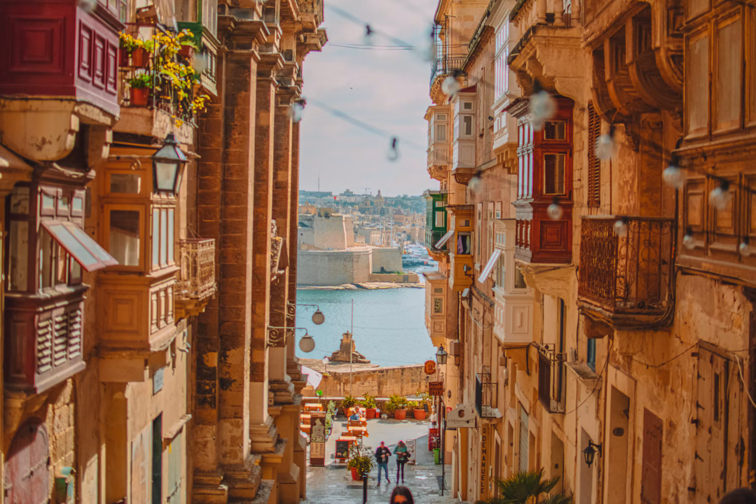 Una calle estrecha en La Valeta con balcones tradicionales de madera que dan al Gran Puerto