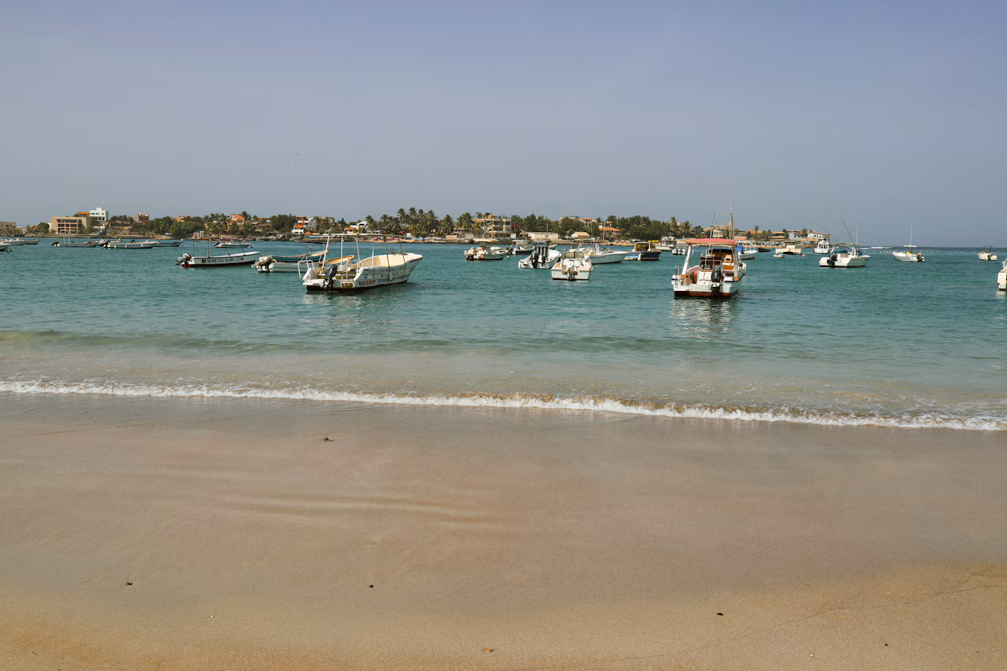 Barcos anclados en una bahía azul tranquila cerca de un pueblo